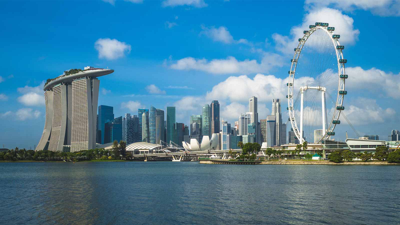 A photograph of the central business district in Singapore – the buildings are reflected in the river and the sky is blue.